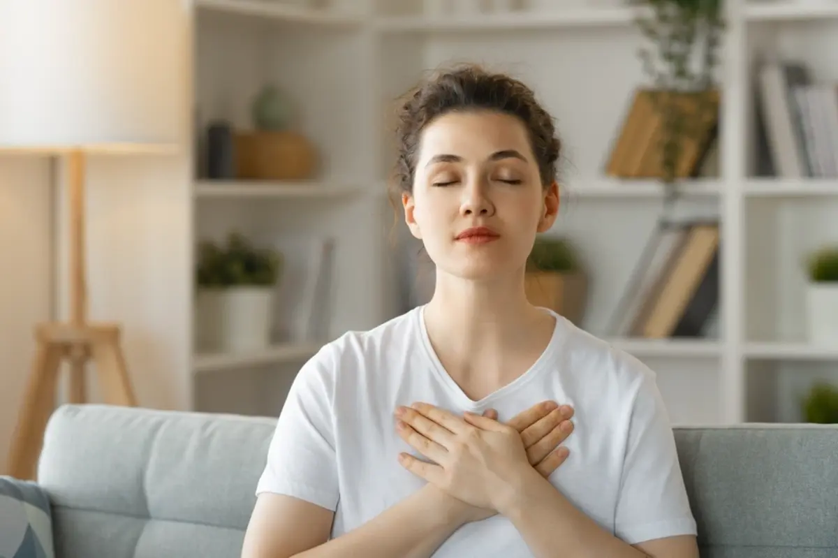 Woman meditating on the couch at home