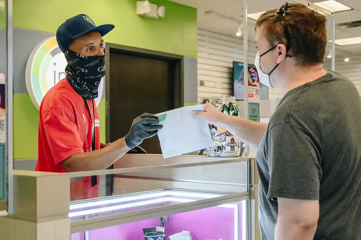 budtender at INYO handling cannabis product to customer