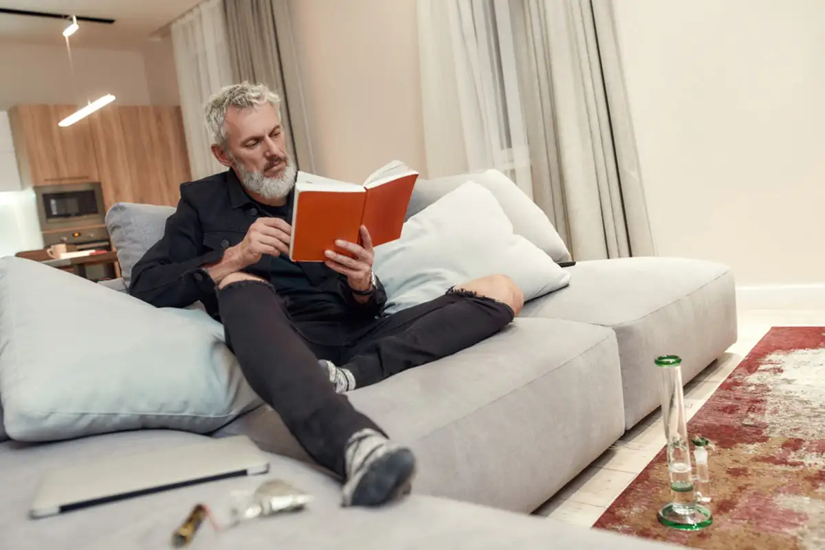 Man sitting on a couch reading a book