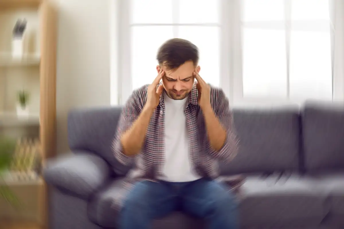 Man suddenly feels dizzy and takes a seat on the sofa