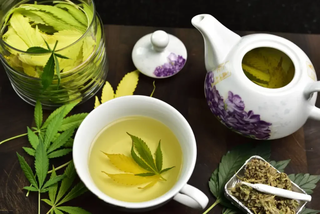 Tea pot with cannabis tea in tea cup on wooden table