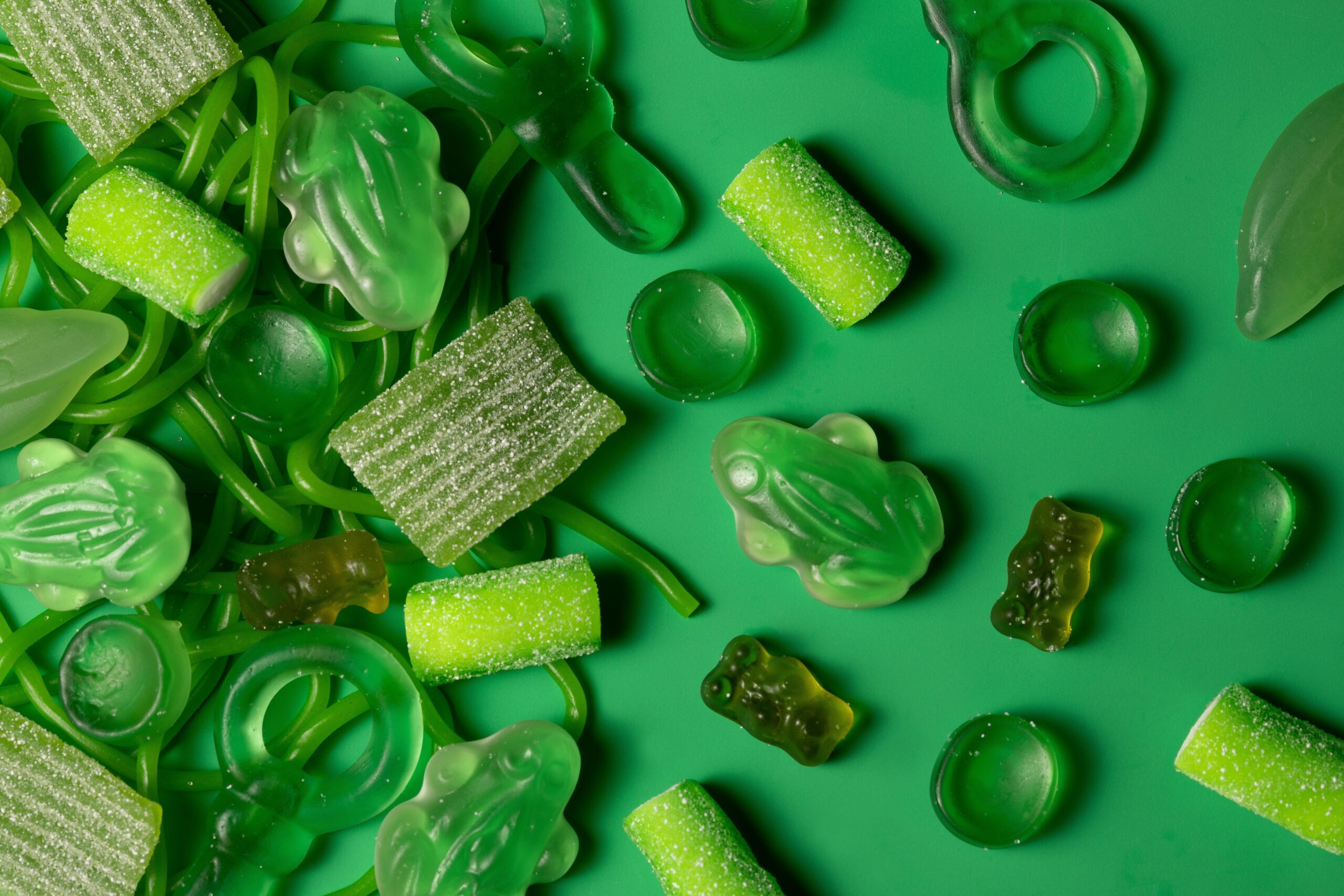 An array of translucent green jelly candies placed on a bright background.
