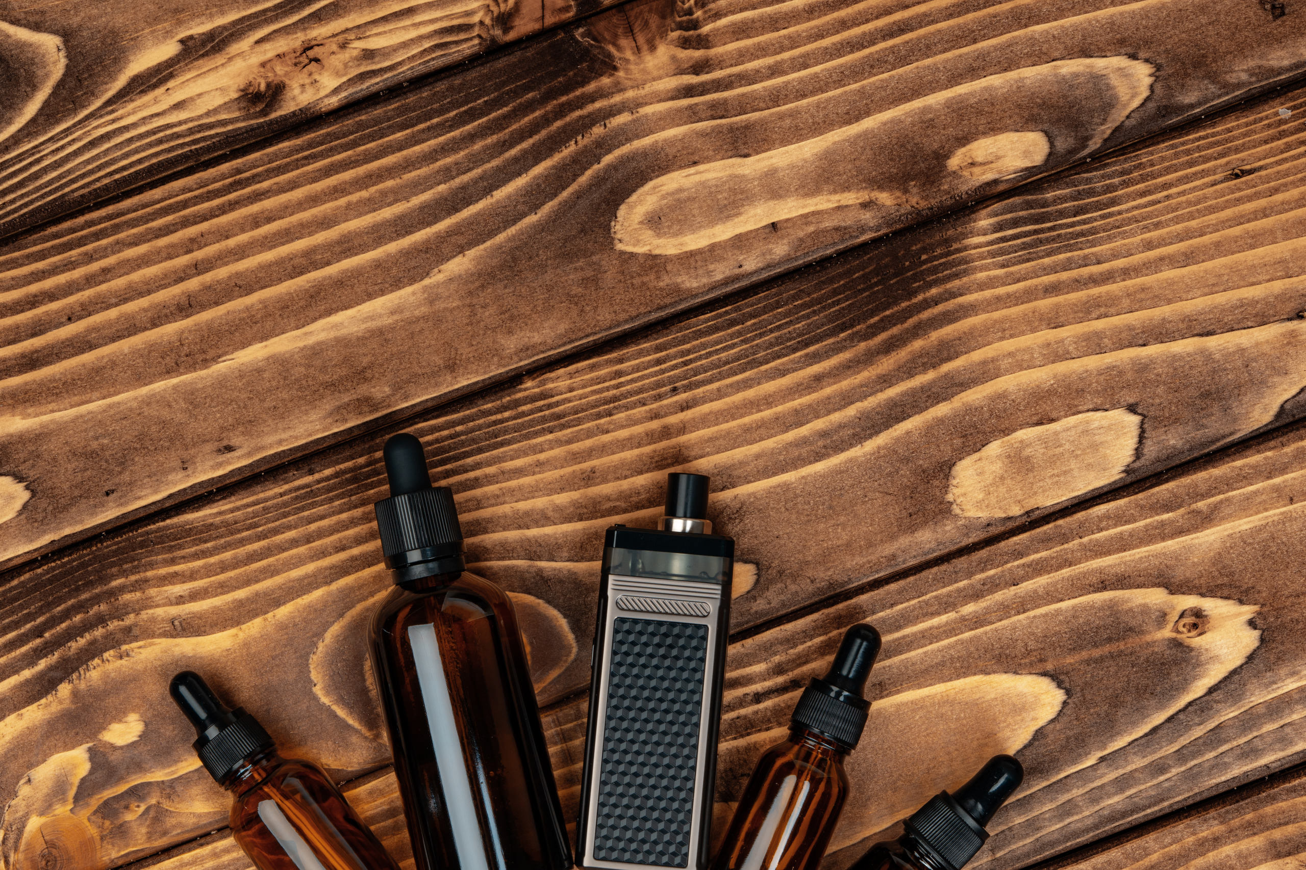 vape-and-vape-juice-bottles-on-brown-wooden-backgr