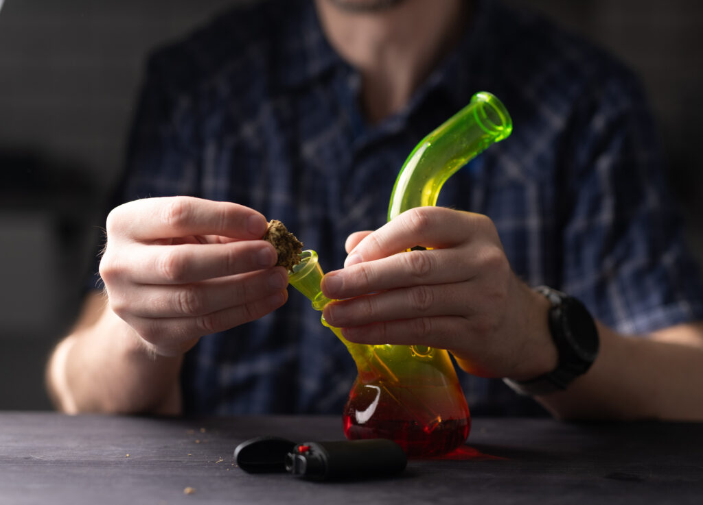 man-fills-bong-with-cannabis-leaves