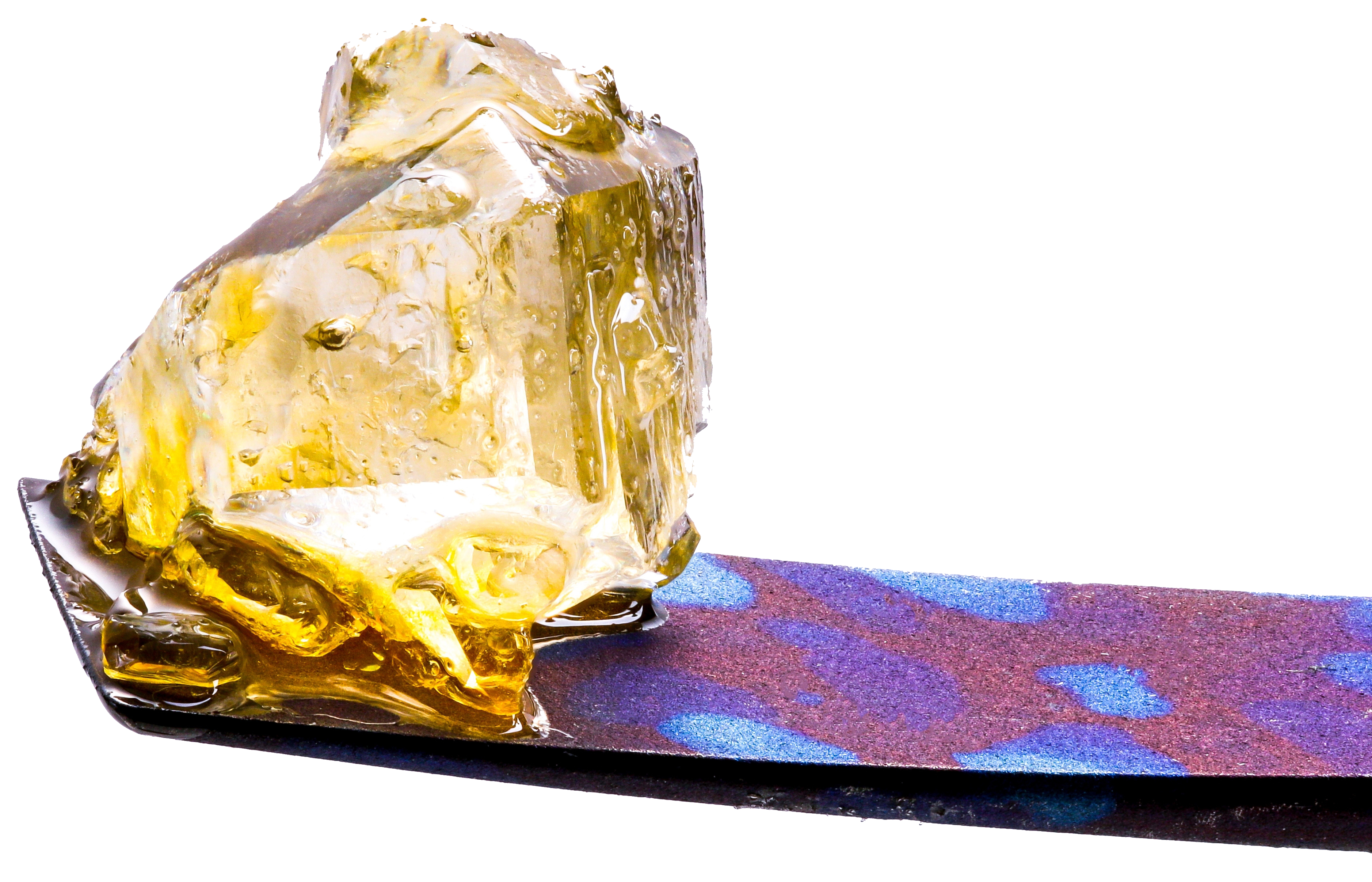 A jagged, translucent amber-colored resin sits on a blue and purple-toned emery board against a black background.